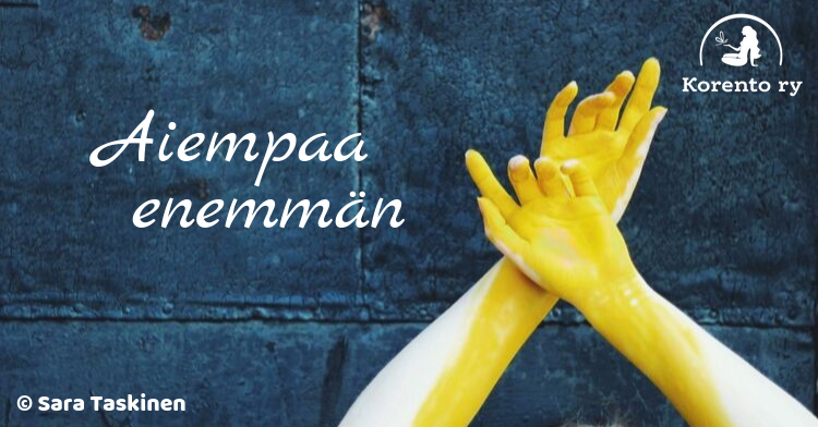 Kuvassa sinertävää tiiliseinää vasten ristissä keltaiseksi värjätyt kädet. Tekstinä bloggaajan nimimerkki; Aiempaa enemmän.